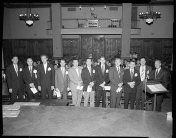 Group of suited men at a meeting in General Office auditorium