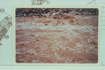 Jean and Hal Bennett in Rapid #22 in Cataract Canyon. Print from dupe owned by the Bennetts. 10,430 cfs. Compare with Davis photo Roll 6 #3 of 1953, July 10, showing change in rocks on shore