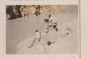 Moore and LaRue taking a panorama picture near the foot of Sockdologer Rapid. Note the dangerous boots worn by Moore