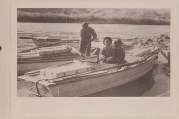 Virginia Lowrey sits in Owen Clark's lap. Val Woodbury coils a line. Lees Ferry. Pathe-Bray Expedition. Copy of print in David C. Lowrey collection