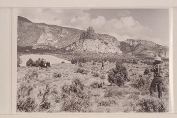 The sandstone butte near the foot of Navajo Mountain. Jorgen Visbak and Frank Masland sit in the Power Wagon. Bahe stands center and Bill Belknap tries for a pictures. War God Spring would be about at upper left of picture