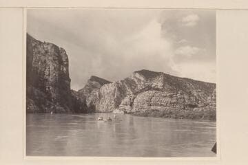 Nevills at the oars of the "Wen" at the foot of Kingfisher Canyon. Al Milotte stands in the bow