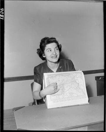 Lady at desk holding up a map of the Middle East
