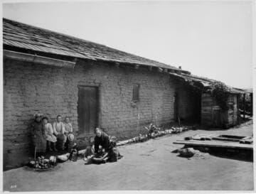 Grinding on metate stone in patio of Aguilar hacienda at San Juan Capistrano