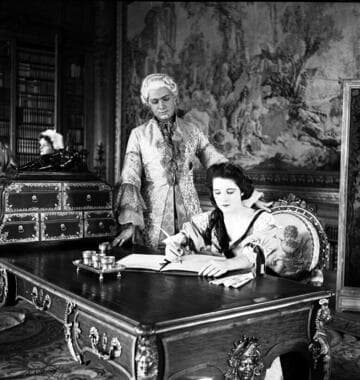 Couple in period costume at a desk in the library of the Huntington residence